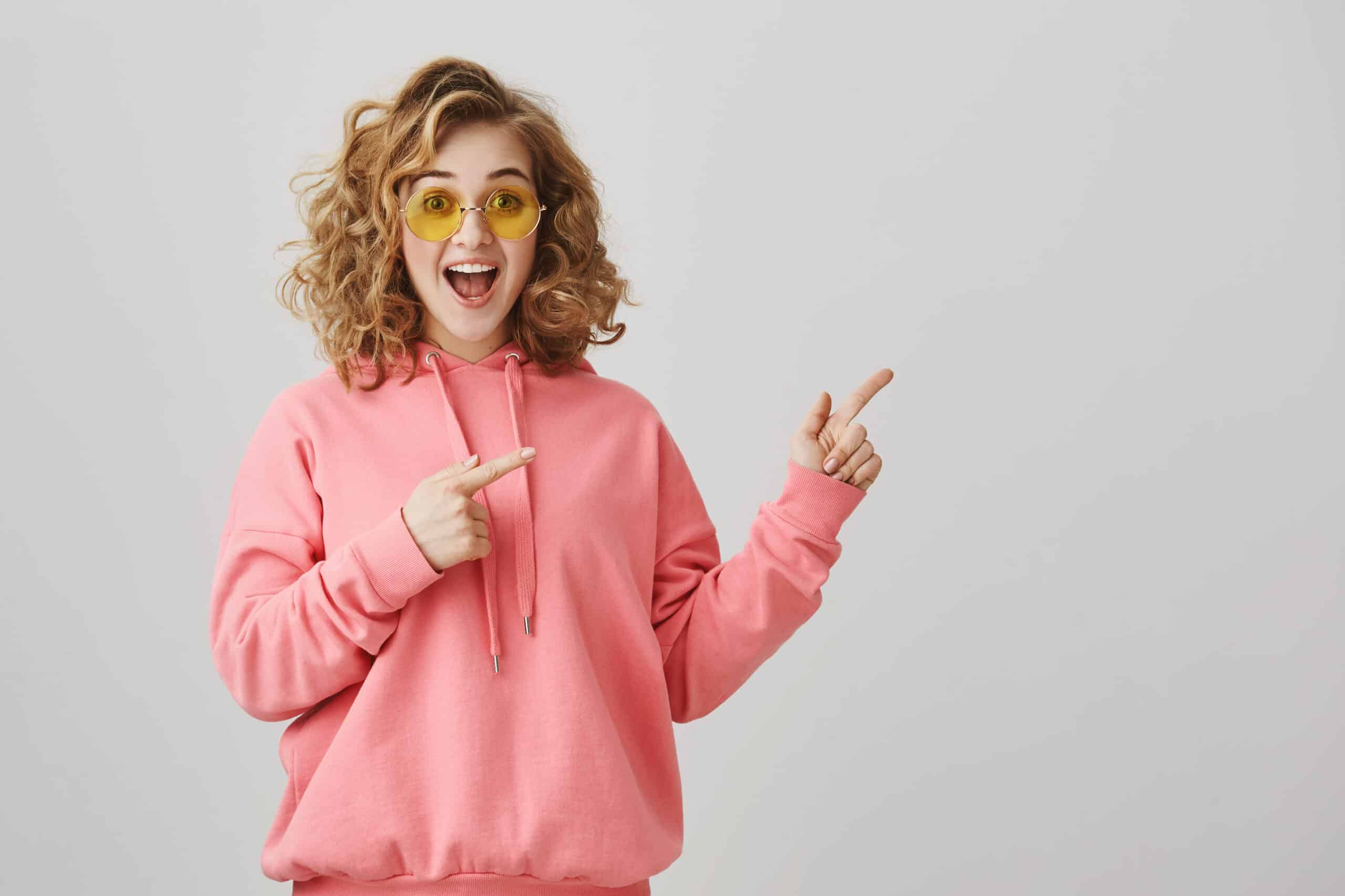 excited stylish curly haired girl sunglasses pointing right showing way scaled